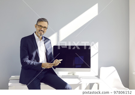 Successful and confident middle-aged business man who posing with modern smartphone in his hands. Successful and confident middle-aged business man who posing with modern smartphone in his hands. 97806152