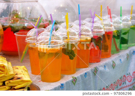 Summer bright drinks with lemon slices, mint and sparkling water in plastic cup with straw. Street food and outdoor cooking concept. Summer bright drinks with lemon slices, mint and sparkling water in plastic cup with straw. Street food and outdoor cooking concept. 97806296