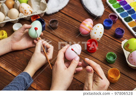 Mother and son are painting Easter eggs. Preparing decorations for Easter 97806528