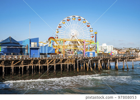 Los Angeles, USA. September 20, 2022. View of ferris wheel and roller coaster at Pacific amusement park facing towards ocean at Santa Monica pier with clear blue sky in background on sunny day Los Angeles, USA. September 20, 2022. View of ferris wheel and roller coaster at Pacific amusement park facing towards ocean at Santa Monica pier with clear blue sky in background on sunny day 97808053