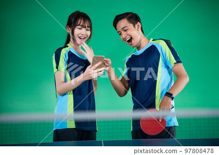 female and male athletes laughing looking at cell phones together female and male athletes laughing looking at cell phones together 97808478