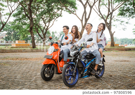 High school student riding motorbike without helmet on park road 97808596