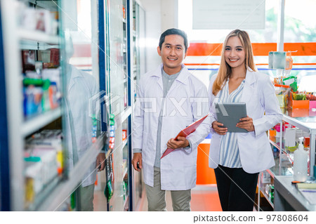 male and female pharmacists in uniforms holding tablets and clipboard male and female pharmacists in uniforms holding tablets and clipboard 97808604
