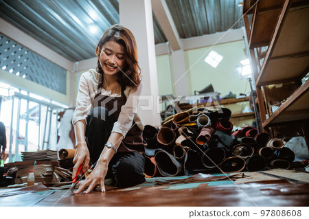 Smiling asian craftswoman working cutting leather on leather material background 97808608