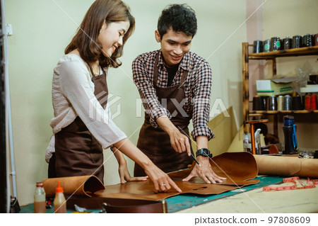 Young asian tailor couple making leather pattern together at work 97808609