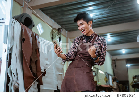 asian craftsman having fun using a smartphone 97808654