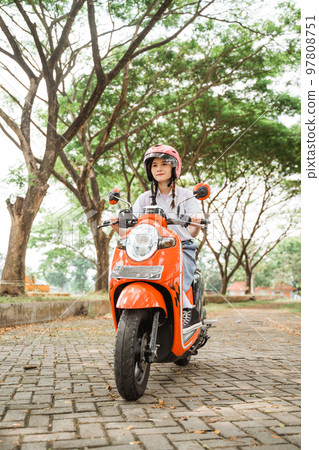 student girl is careful riding a motorcycle wearing a helmet 97808751