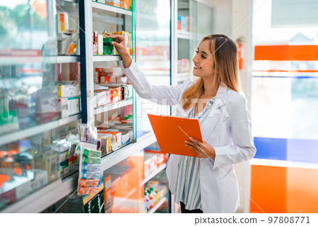 female pharmacist in uniform working checking medicine by observing female pharmacist in uniform working checking medicine by observing 97808771