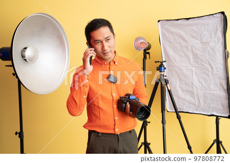 photographer holding professional camera while making phone call photographer holding professional camera while making phone call 97808772
