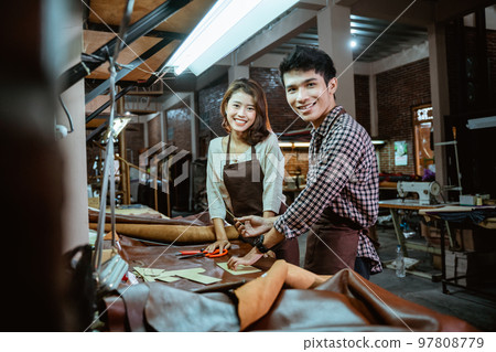 Asian male and female leather worker smiling in his studio Asian male and female leather worker smiling in his studio 97808779