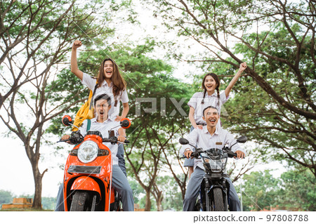 Two pairs of high school students celebrate graduation by motorbikes Two pairs of high school students celebrate graduation by motorbikes 97808788