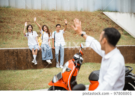 Three high school kids meet a male friend who came by motorbike Three high school kids meet a male friend who came by motorbike 97808801