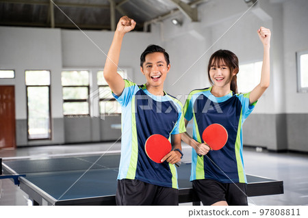 Two ping pong players holding paddles with raised fists 97808811