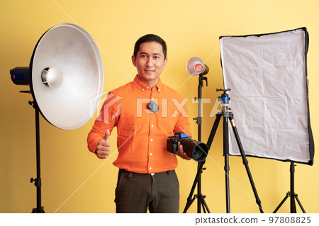 photographer standing with thumbs up and holding camera 97808825