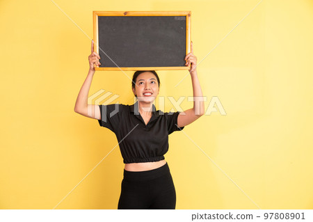 woman glancing up standing holding blackboard above head woman glancing up standing holding blackboard above head 97808901