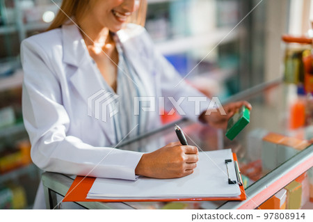 pharmacist's hand using pen writes the name of the drug 97808914