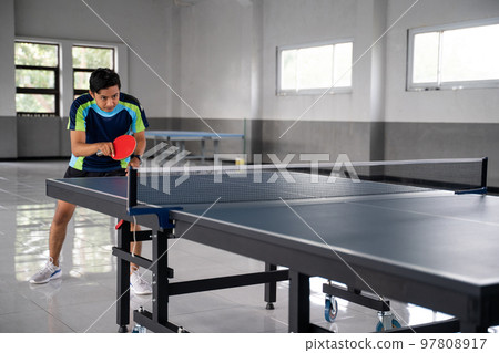 Asian male ping pong player ready to receive service ball Asian male ping pong player ready to receive service ball 97808917