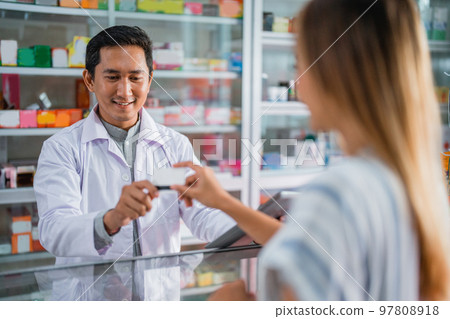 male pharmacist in uniform accepting cashless payment by atm card male pharmacist in uniform accepting cashless payment by atm card 97808918