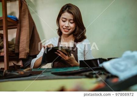 Woman craftsman holding pieces of tanned leather making leather apron Woman craftsman holding pieces of tanned leather making leather apron 97808972