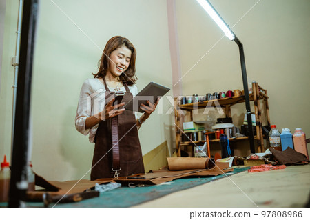 Asian craftswomen use digital tablets to find references Asian craftswomen use digital tablets to find references 97808986