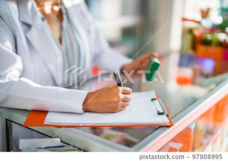close up of pharmacist working writing drug list with pen and clipboard close up of pharmacist working writing drug list with pen and clipboard 97808995