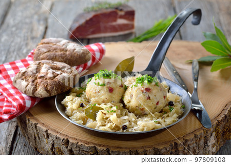 Delicious South Tyrolean bacon dumplings served on sauerkraut in an iron frying pan Delicious South Tyrolean bacon dumplings served on sauerkraut in an iron frying pan 97809108
