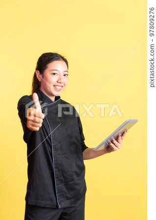 smiling asian female chef using a pad with thumbs up smiling asian female chef using a pad with thumbs up 97809276