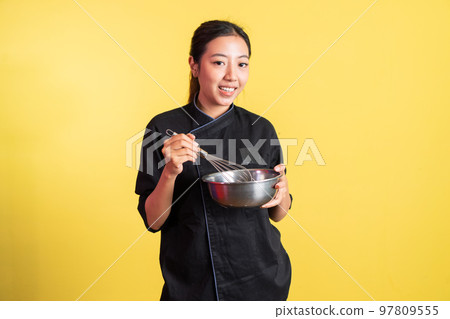 Asian female chef carrying stainless basin and holding whisk 97809555