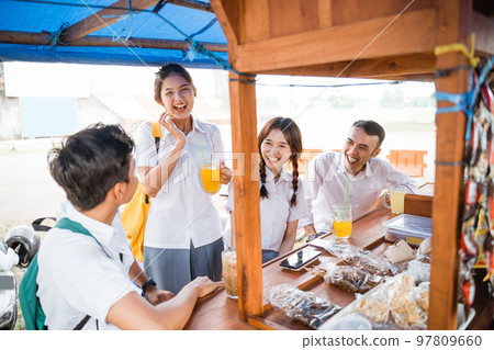 Four high school kids in uniform joking while eating 97809660