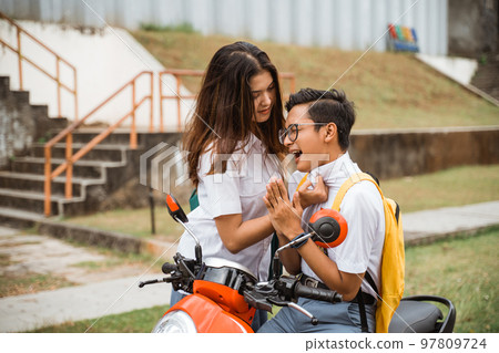 Tomboy girl student challenges boy student while riding a motorbike Tomboy girl student challenges boy student while riding a motorbike 97809724