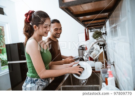 attractive young woman and asian man washing dishes together 97809770