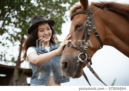 beautiful asian cowboy girl standing beside horse on outdoor background beautiful asian cowboy girl standing beside horse on outdoor background 97809864