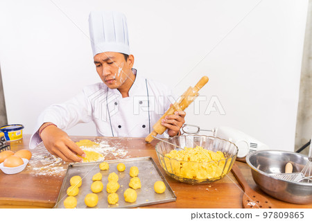 male chef with smug face making cake with rolling pin male chef with smug face making cake with rolling pin 97809865