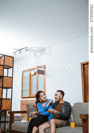 beautiful girl feeds a snack to boyfriend on the sofa 97809882