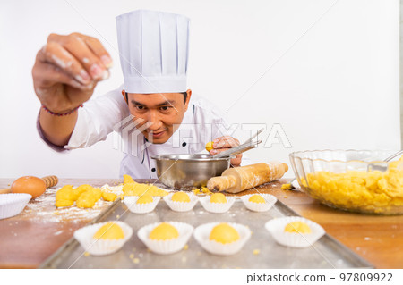 male chef carefully sprinkles topping on cake on tray male chef carefully sprinkles topping on cake on tray 97809922
