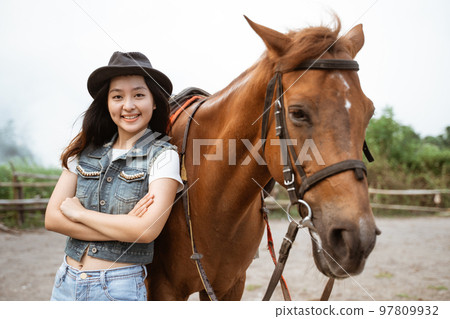 beautiful asian cowboy girl standing beside horse on outdoor background beautiful asian cowboy girl standing beside horse on outdoor background 97809932