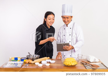 two chefs using a pad before processing food ingredients two chefs using a pad before processing food ingredients 97809935