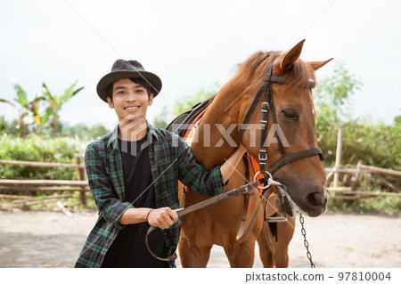 man in cowboy hat smiling while stroking the head horse man in cowboy hat smiling while stroking the head horse 97810004