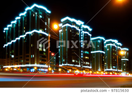 Night city. Photo with motion blur effect. Modern residential multi-storey house with illumination Night city. Photo with motion blur effect. Modern residential multi-storey house with illumination 97815630
