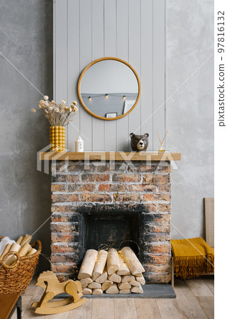 Scandinavian brick fireplace with wood and decor on it against the background of a gray wall of a country house Scandinavian brick fireplace with wood and decor on it against the background of a gray wall of a country house 97816132