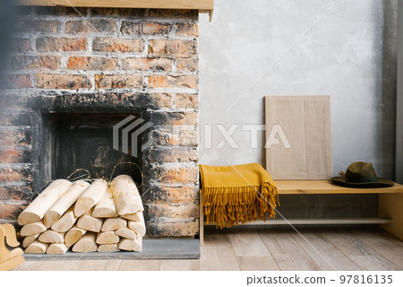 A fireplace with wood and a blanket on the bench next to it in a rustic Scandinavian style 97816135
