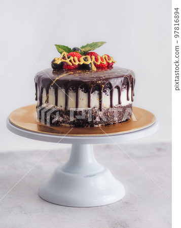 dark chocolate frosted drip cake with best wishes topping written in italian 97816894