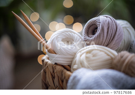 Cozy homely atmosphere. Female hobby knitting. Yarn in neutral shades in a basket Cozy homely atmosphere. Female hobby knitting. Yarn in neutral shades in a basket 97817686