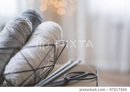 Cozy homely atmosphere. Female hobby knitting. Yarn in neutral shades in a black iron wire basket. 97817806