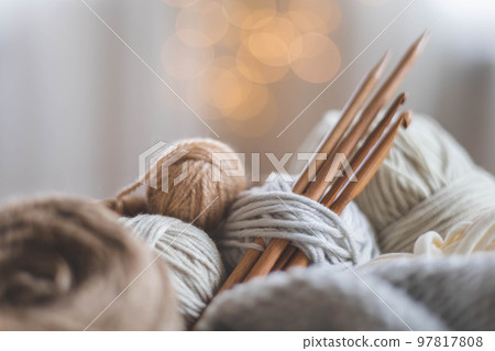 Cozy homely atmosphere. Female hobby knitting. Yarn in neutral colors. 97817808