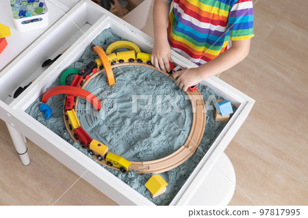 Cute baby boy confident playing railroad train toy on sand table therapy childish early development 97817995