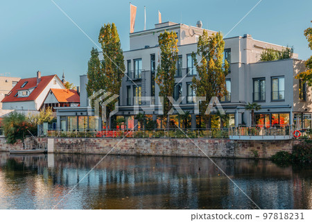 River On Sunset. Townhouses Buildings And Multi-floor Home At Waterfront. Sunset On River In City. Suburb Houses And Residential Building Near River In Europe. House In Nature On Shore On Sunset. 97818231