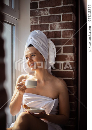 Closeup relaxed morning woman wearing white towel drinking coffee eating jam croissant 97818233