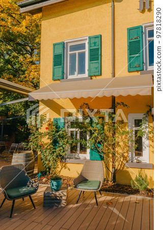 Image of a empty coffee tables arranged in backyard of a house. Autumn in Germany, Europe. Outdoor table in street cafe. autumn outdoor cafe wooden furniture old europe. Autumn photo of old-fashioned 97818290