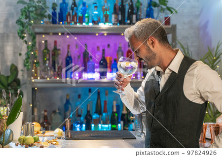 Professional barman smelling cocktail in nightclub. Night life concept 97824926
